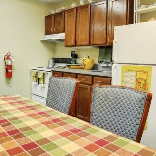 A cozy kitchen with a checkered tablecloth on the dining table and wooden cabinets.