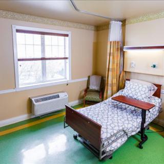 A clean and bright hospital room with a single bed near the window.