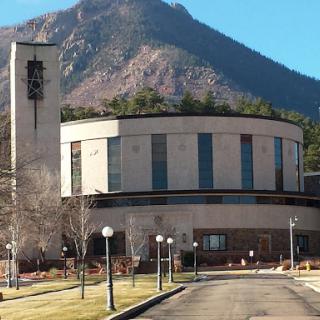 A modern building set against a mountainous backdrop.