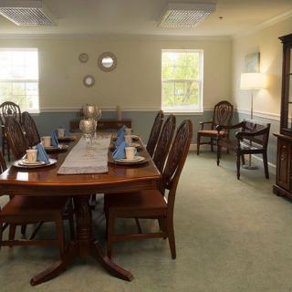 A well-furnished dining room with a long wooden table set for a meal, surrounded by elegant chairs and decorated with home dcor accents.