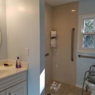 An accessible bathroom featuring a walk-in shower with grab bars and a vanity sink.