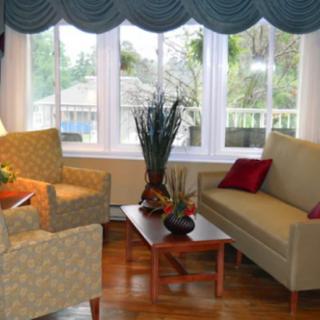 A cozy living room with a sofa, armchairs, and a coffee table near large windows.