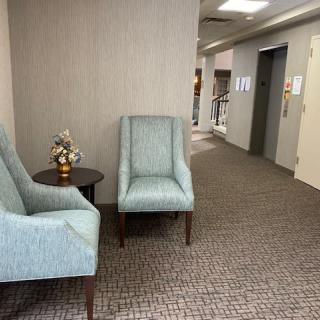 A quiet office lobby with two chairs and an elevator.