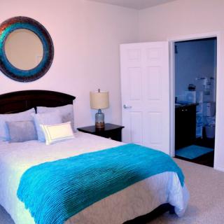 A cozy bedroom with a bed, decorative mirror, and a lamp by the nightstand.