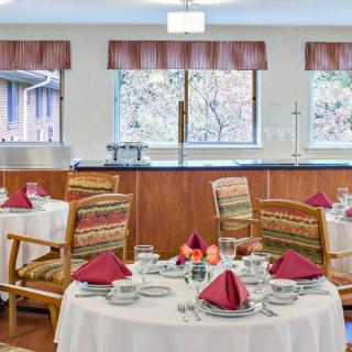 A cozy dining room with elegantly set tables and chairs near large windows.