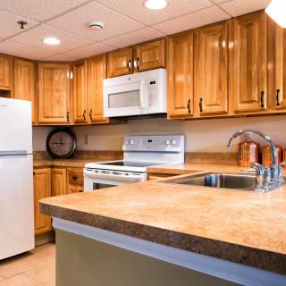 A modern kitchen with wooden cabinets and a range of appliances, including a refrigerator, oven, and microwave.