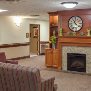 A cozy lounge area with a fireplace and clock, featuring comfortable seating and warm decor.