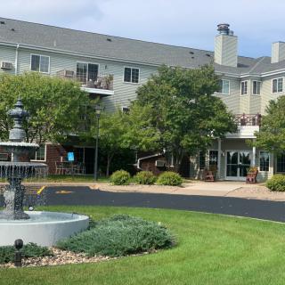 A spacious residential building with well-maintained landscaping and a fountain in the foreground.