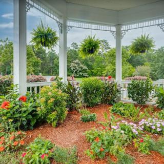 A beautiful garden with vibrant flowers and hanging plants under a gazebo.