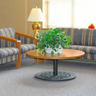 A cozy living room setup with a round coffee table, plant, and striped sofas.