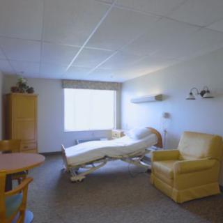 A clean hospital room with essential furniture including a bed, chair, and window.