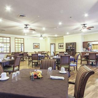 An empty dining room with neatly set tables and chairs, featuring warm lighting and tasteful decor.
