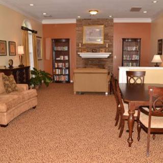 A cozy living room with a sofa, bookshelves, and a dining table near a fireplace.