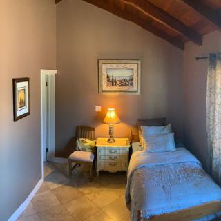 A cozy bedroom with a single bed, nightstand, and lamp under a vaulted ceiling.