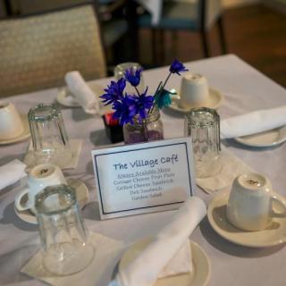 A neatly arranged table at The Village Cafe, featuring flowers and a menu card.