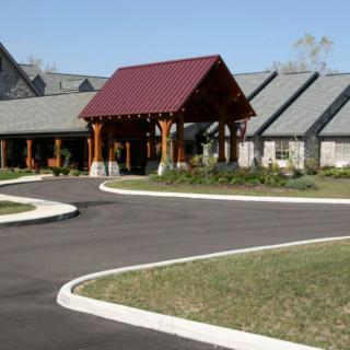 A modern building with a covered entrance and landscaped driveway.