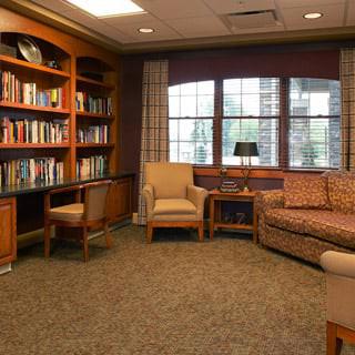 A cozy library corner with bookshelves, comfortable seating, and natural light.