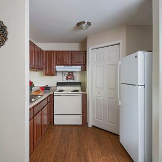 A compact kitchen with wooden cabinets, a white fridge, and stove.