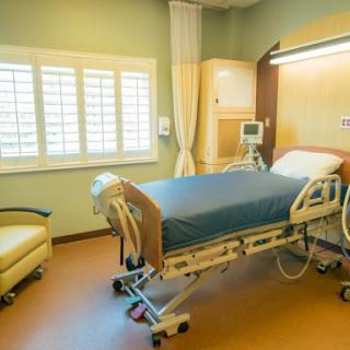 A well-lit hospital patient room featuring a medical bed and comfortable chair.