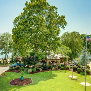 A beautiful garden with lush greenery and a house in the background, featuring a well-kept lawn and flagpole.