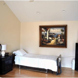 A minimalist bedroom with a single bed, nightstands, and a landscape painting on the wall.