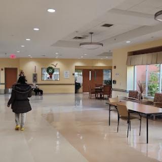 A spacious lobby area with tables and chairs, featuring warm lighting.