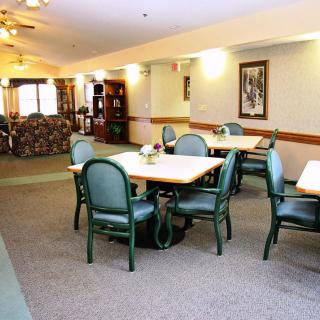 A well-lit indoor dining area with tables and chairs, featuring a cozy carpeted floor.