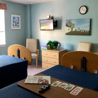 Hospital room with two beds, a television, and a window.