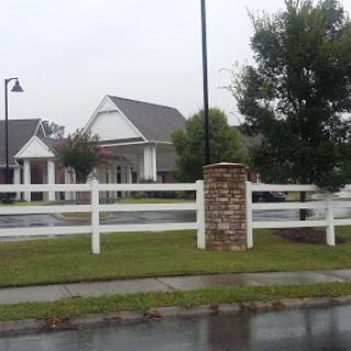 A charming residential house with a white fence, set against a backdrop of rainy clouds.