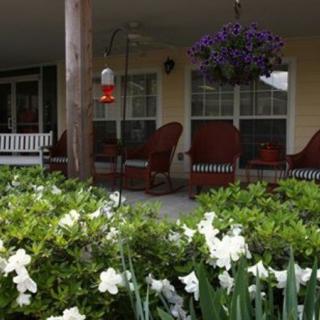 A cozy porch with comfortable seating overlooks a garden filled with blooming flowers.