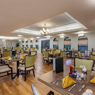 An elegant restaurant dining room with neatly arranged tables and chairs, featuring warm lighting and tasteful decor.