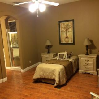 A cozy bedroom with a single bed, nightstands, and warm lighting.