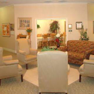 A cozy living room with a seating area featuring chairs and a sofa, decorated with plants and artwork.