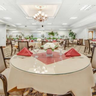 An elegant dining room with neatly set tables and a chandelier hanging from the ceiling.