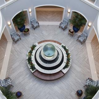Aerial view of a circular atrium featuring a central fountain surrounded by seating and plants.