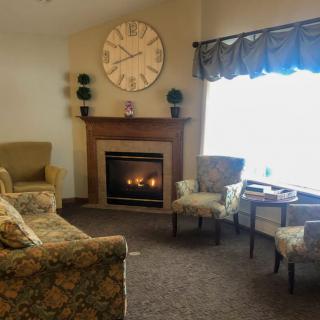 A cozy living room with a fireplace and a large wall clock.
