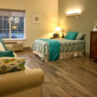 A cozy bedroom with teal accents and warm lighting, featuring a single bed and wooden flooring.