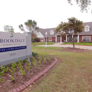 A residential building with a sign reading 'Brookdale' amidst a well-maintained lawn and trees.