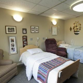 A well-lit hospital room featuring two beds, a comfortable chair, and decorative elements on the walls.