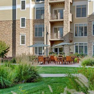 A modern apartment building with a landscaped garden and outdoor seating area.