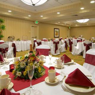 A beautifully arranged dining space set for an elegant event, featuring white tablecloths and red accents.