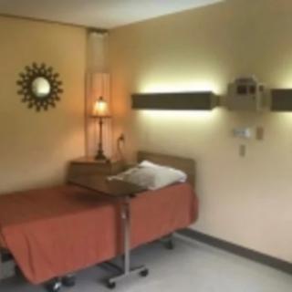 A hospital room with a single bed and warm lighting.
