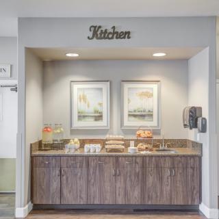 A cozy kitchen nook featuring a snack and coffee station with decorative artwork.