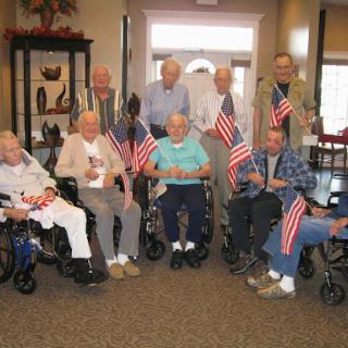 A heartwarming gathering of elderly individuals holding American flags in a community center.