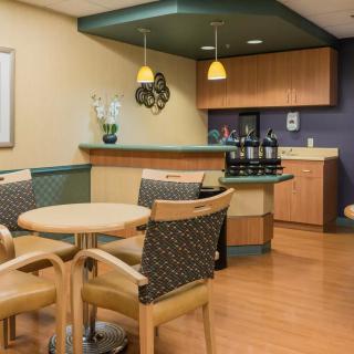 A cozy waiting area with tables, chairs, and a coffee station.