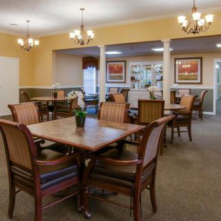 A well-furnished dining room with multiple tables and chairs, accented by chandeliers and wall art.