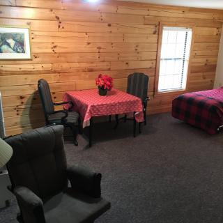 Cozy cabin interior with wood paneling, featuring a table and chairs, and a bed.