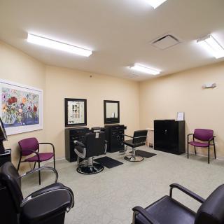 An interior view of a barbershop with chairs, mirrors, and a waiting area.