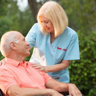 A healthcare professional providing compassionate support to a senior citizen in an outdoor environment.