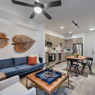 A modern living room with an open floor plan, featuring a comfortable sofa and a dining area adjacent to the kitchen.